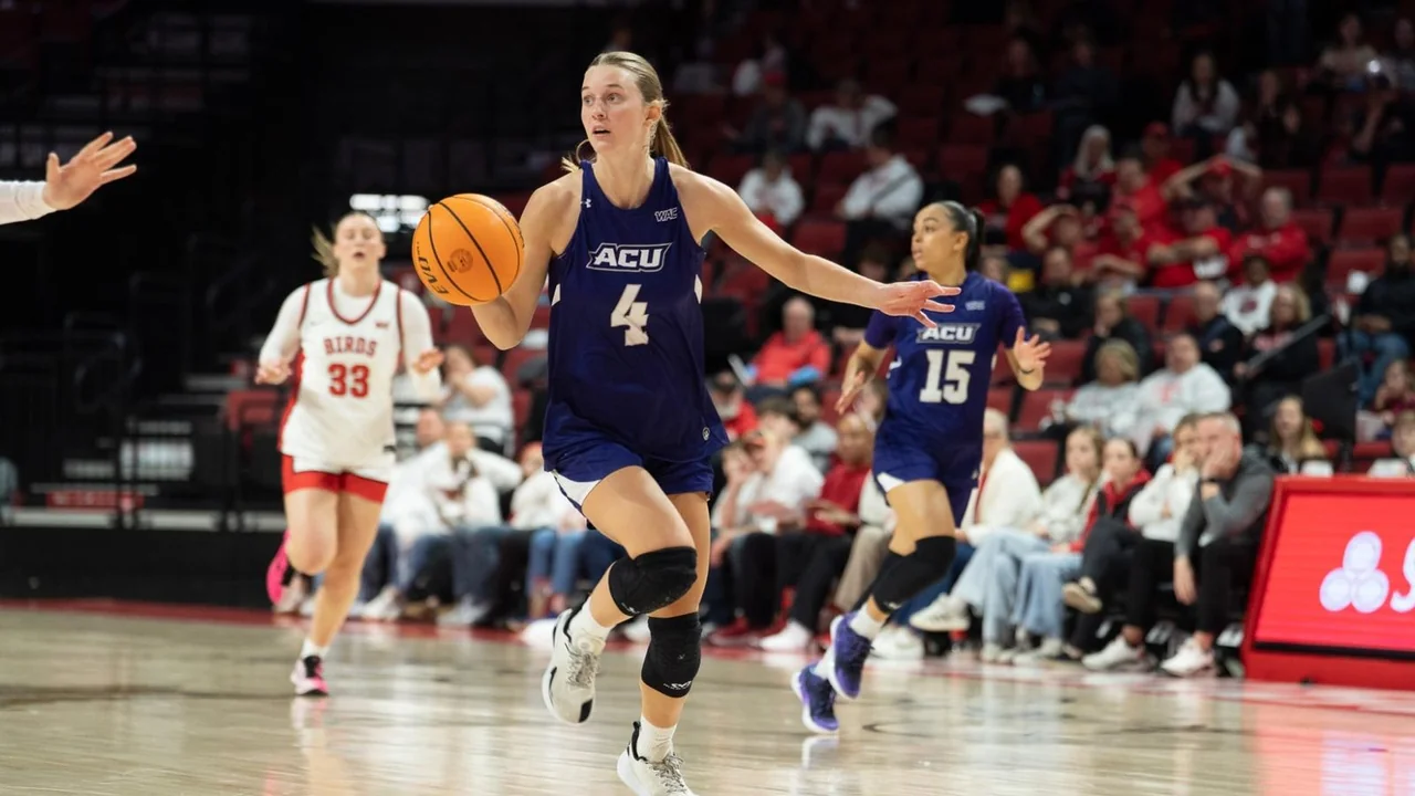 Abilene Christian Wildcats women's basketball: player moving with the ball as opponents defend on court