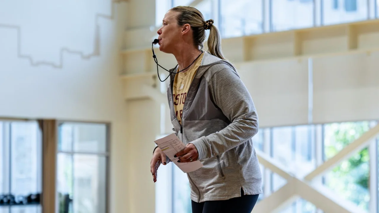Boston College Eagles women's basketball: coach holding a basketball beside large windows