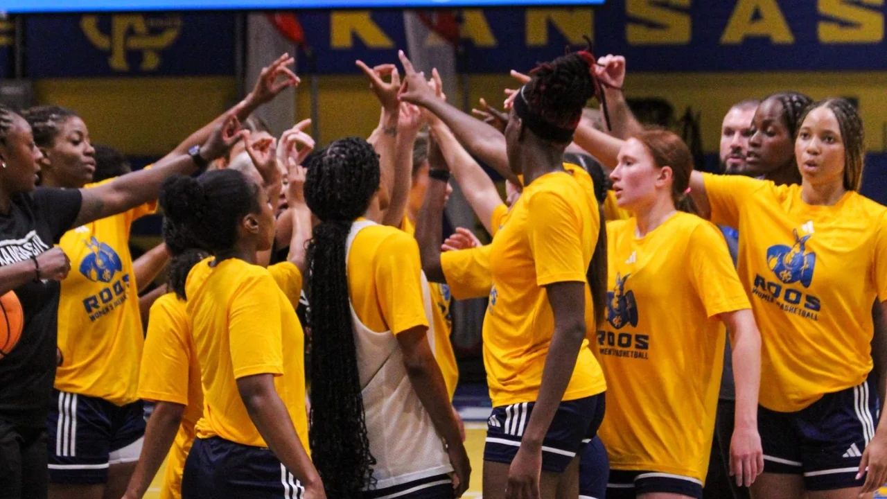 Kansas City Roos women's basketball: players standing together in yellow warmup shirts