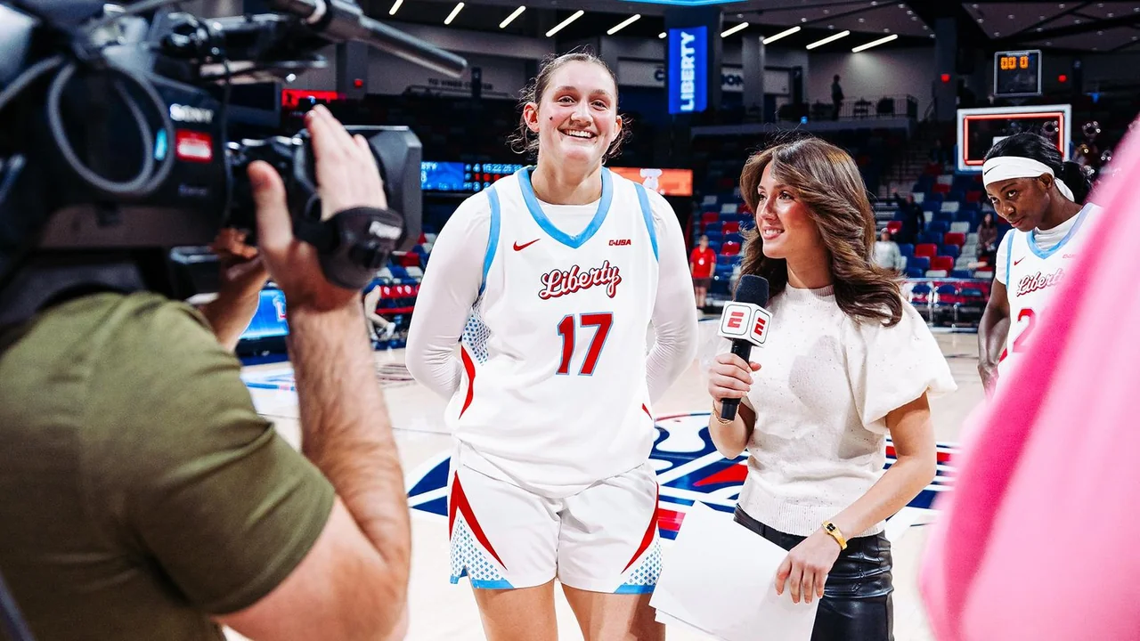 Liberty Flames women's basketball: player smiling while greeting people beside the court