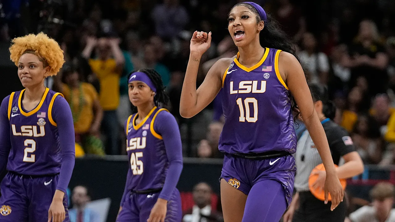 LSU Tigers player pumping her fist in celebration during a game with teammates behind her