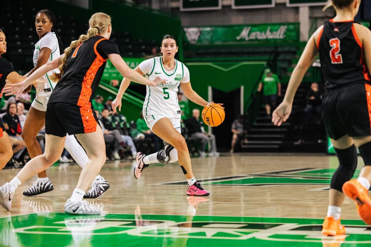 Marshall Thundering Herd women's basketball: player dribbling between defenders during a home game