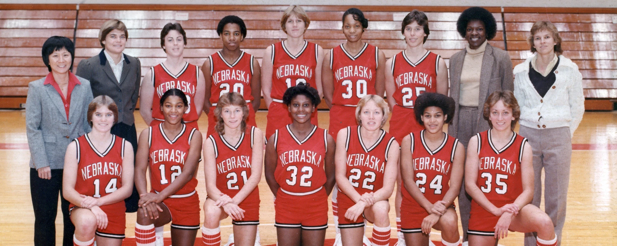 Archival color team photo of an early Nebraska Cornhuskers women's basketball squad with coaching staff