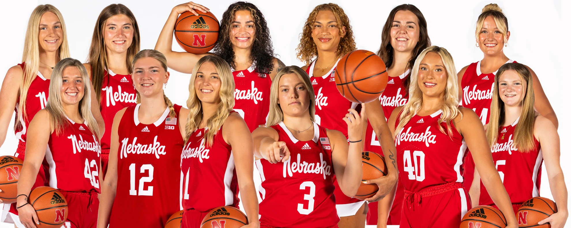 Nebraska Cornhuskers women's basketball team photo with players in red jerseys posing with basketballs on a white backdrop
