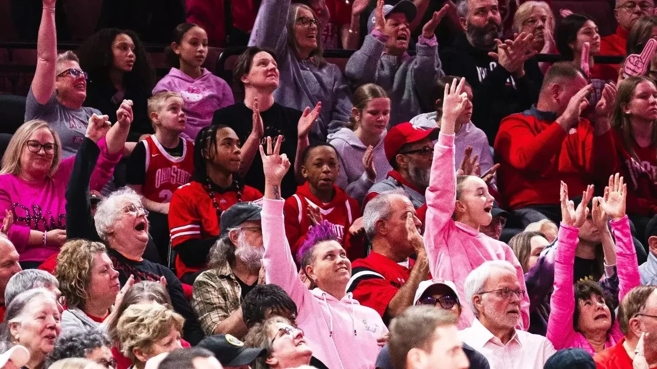 Ohio State Buckeyes women's basketball: players in pink warmups celebrating beside the court