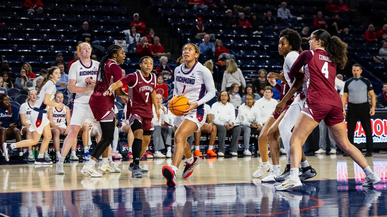 Richmond Spiders women's basketball: player controlling the ball during a game in front of the bench