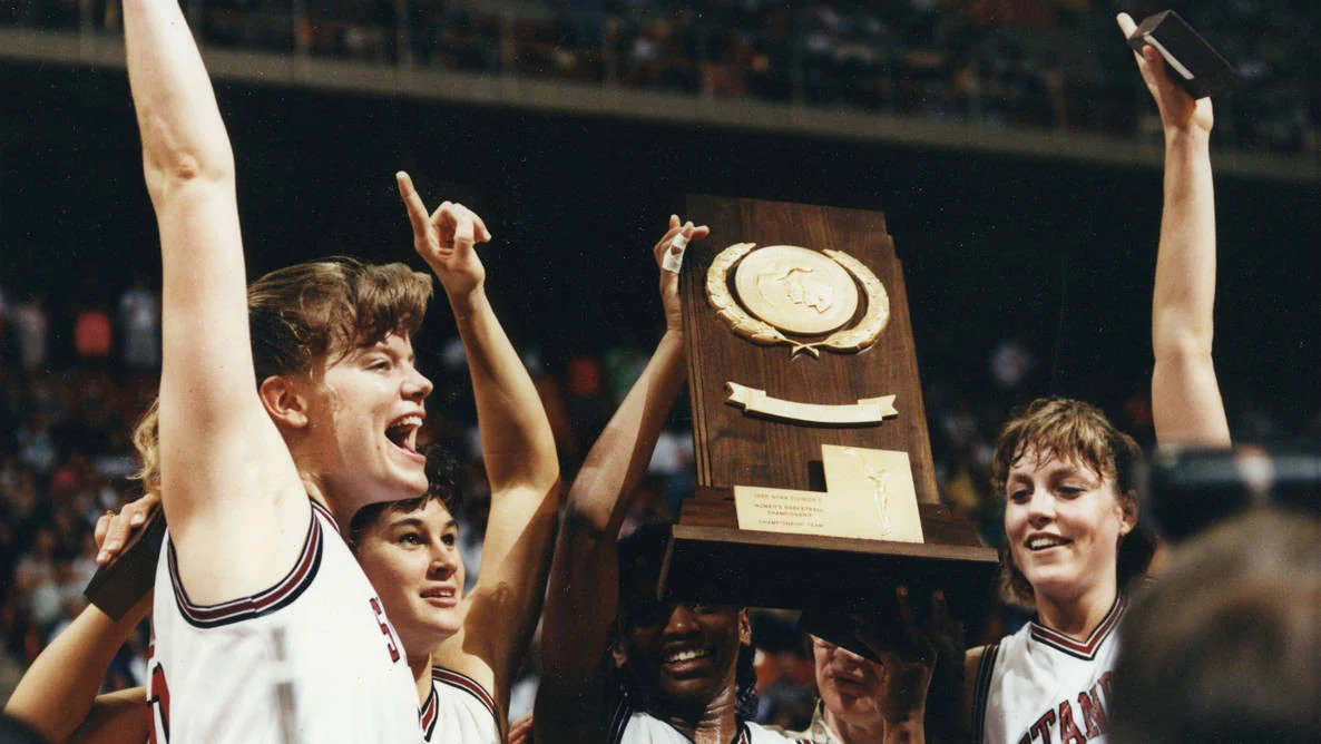 Stanford Cardinal women's basketball: archival image of players celebrating with a championship trophy