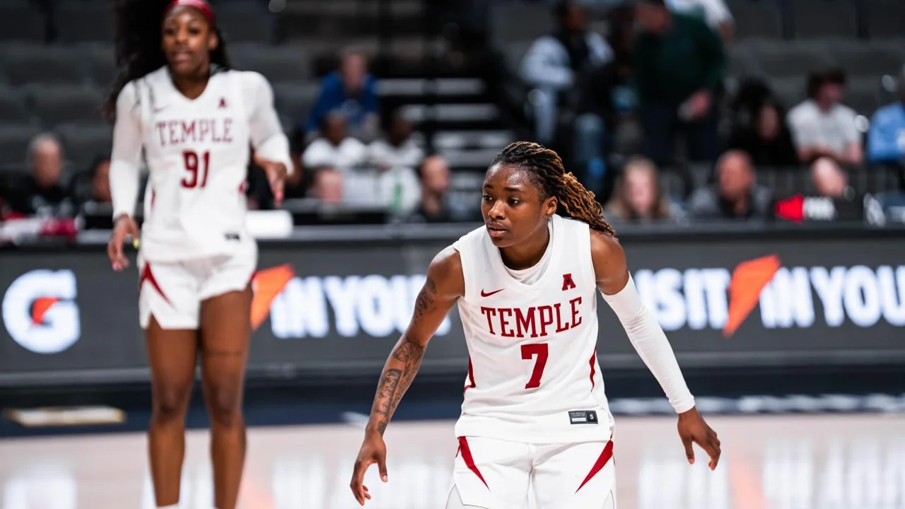 Temple Owls women's basketball: player dribbling during a game in a white Temple uniform