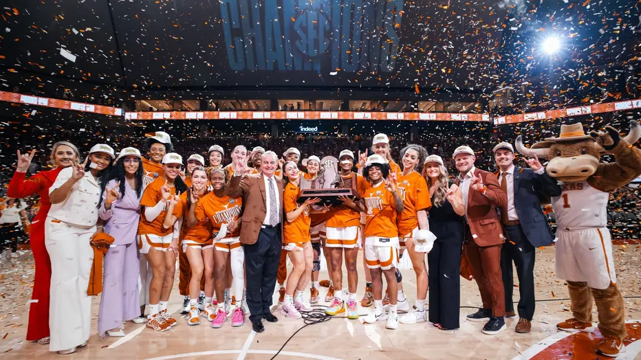 Texas Longhorns players and staff celebrating with a championship trophy under falling confetti