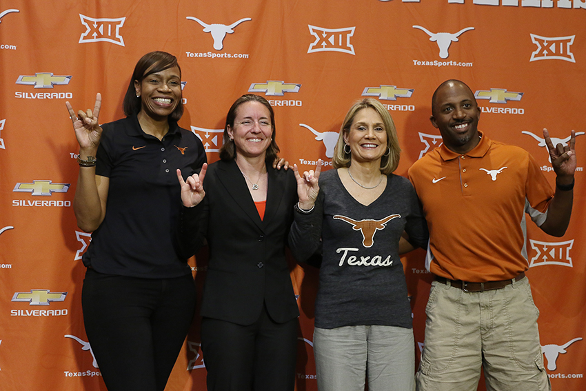 Four Texas women's basketball coaching staff members posing together in front of a Big 12 branded backdrop