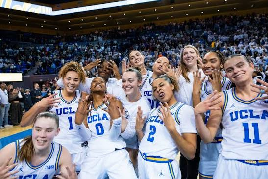 UCLA Bruins players huddled together smiling and celebrating after a win
