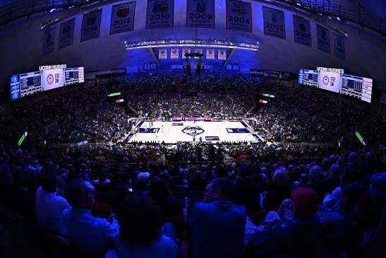 Gampel Pavilion crowd viewed from the upper deck with championship year banners lit above the court