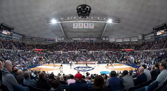 Wide interior view of Gampel Pavilion packed with fans during a UConn Huskies home game, with championship banners hanging from the rafters