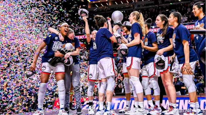 UConn Huskies players celebrating with a championship trophy under falling confetti