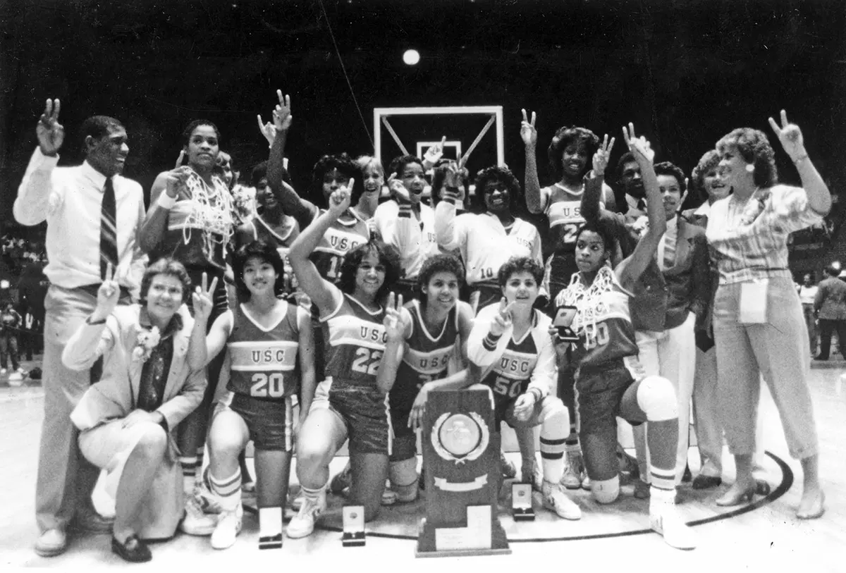 Archival black-and-white photo of USC players celebrating a national championship with a trophy and cut-down nets