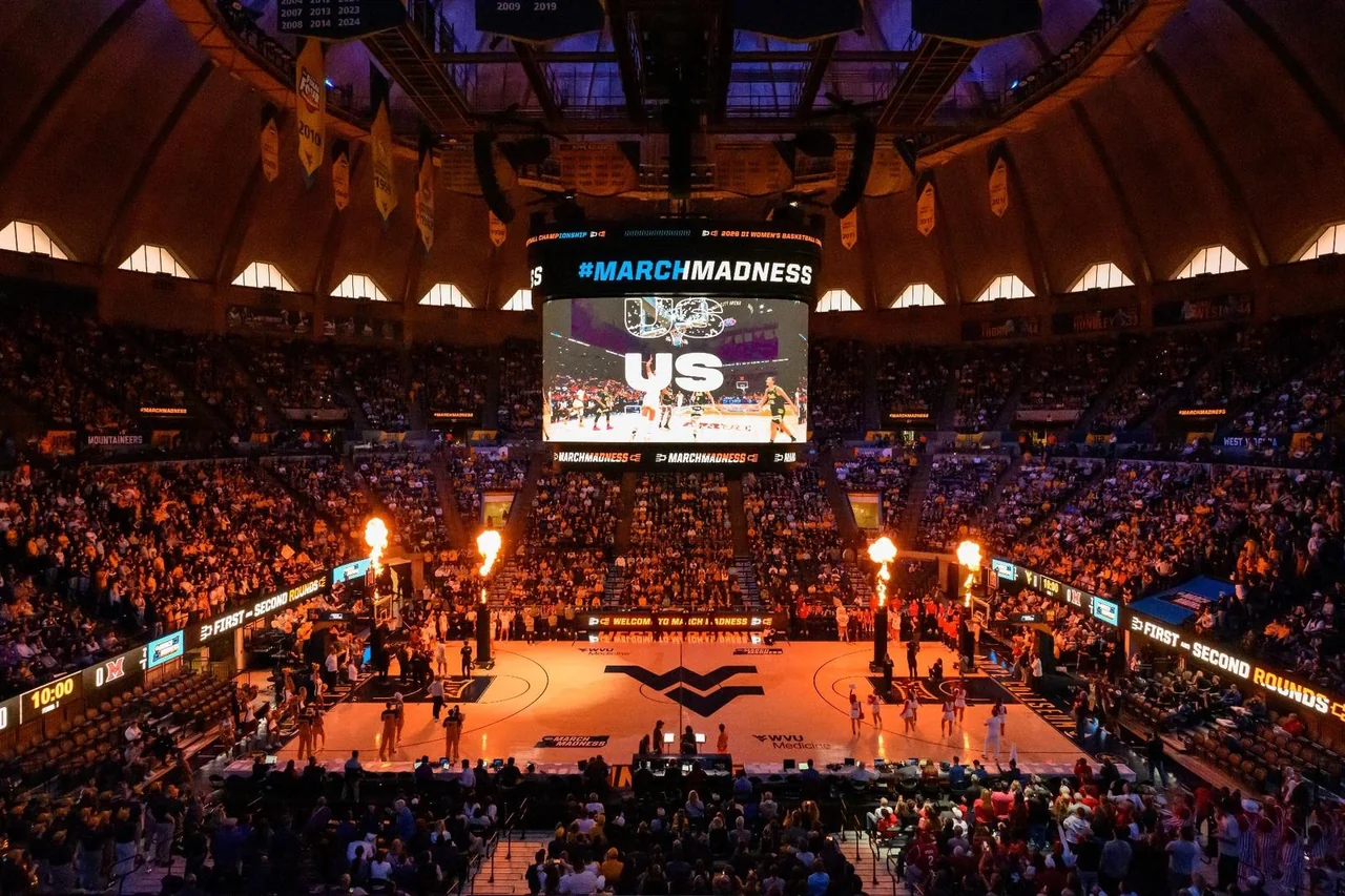 West Virginia Mountaineers women's basketball: basketball arena filled with fans beneath the roof lights